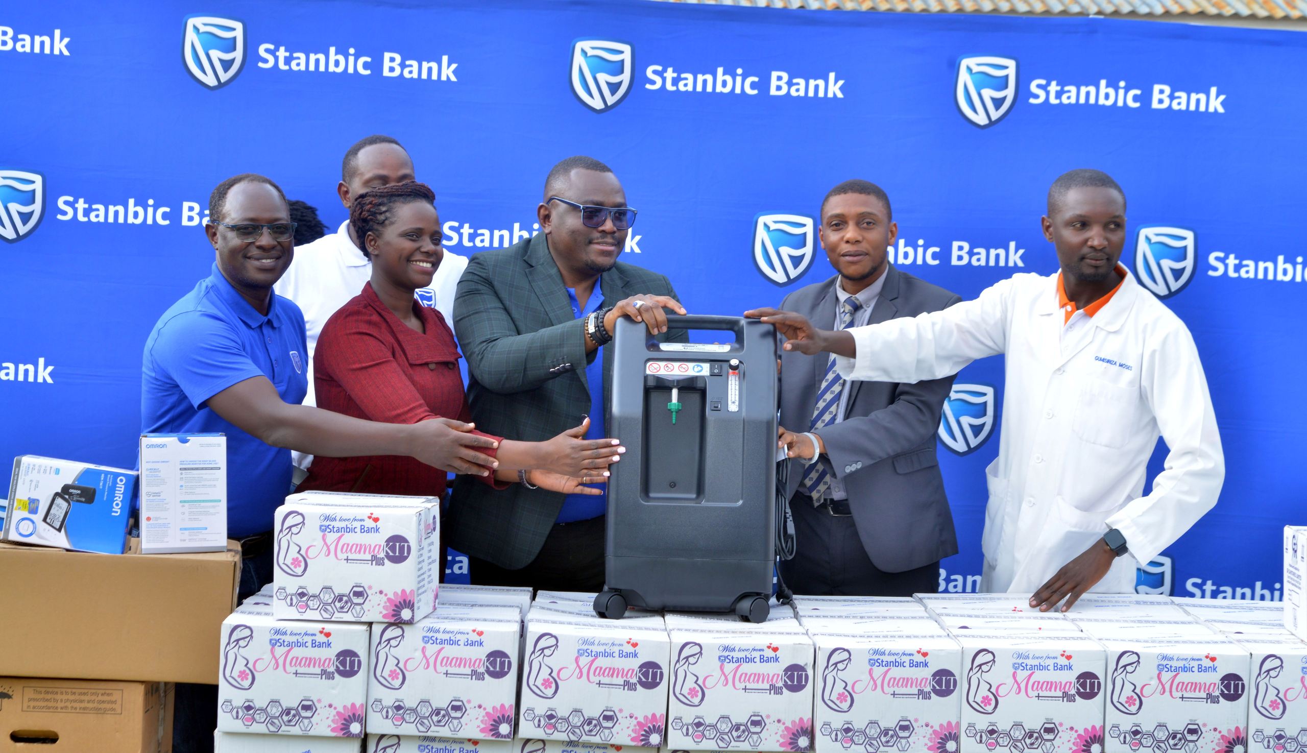 Stanbic Regional Manager Benard Ogwal, Busaiga SACCO's Mercy Kusemererwa and StaTunde Thorpe handing over the equipement to Dr. Brian Kisembo, Karobarole ast. DHO and Moses Gumisiriza the Facility In Charge
