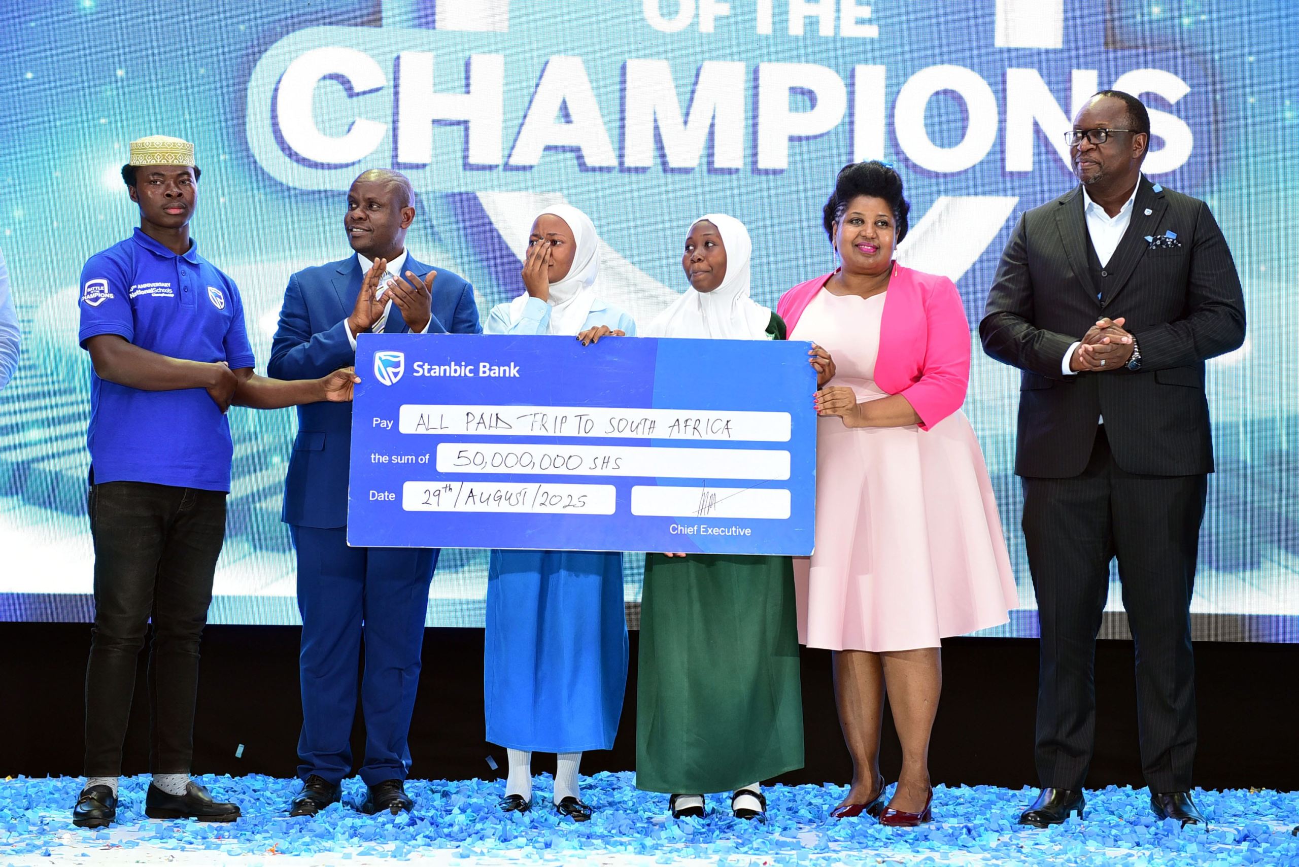 Mumba Kalifungwa (R) Stanbic Bank Chief Executive together with Minister Balaam Barugahara and PSFU's Sarah Kagingo handing over the travel dummie cheque to Sumaya Girls students
