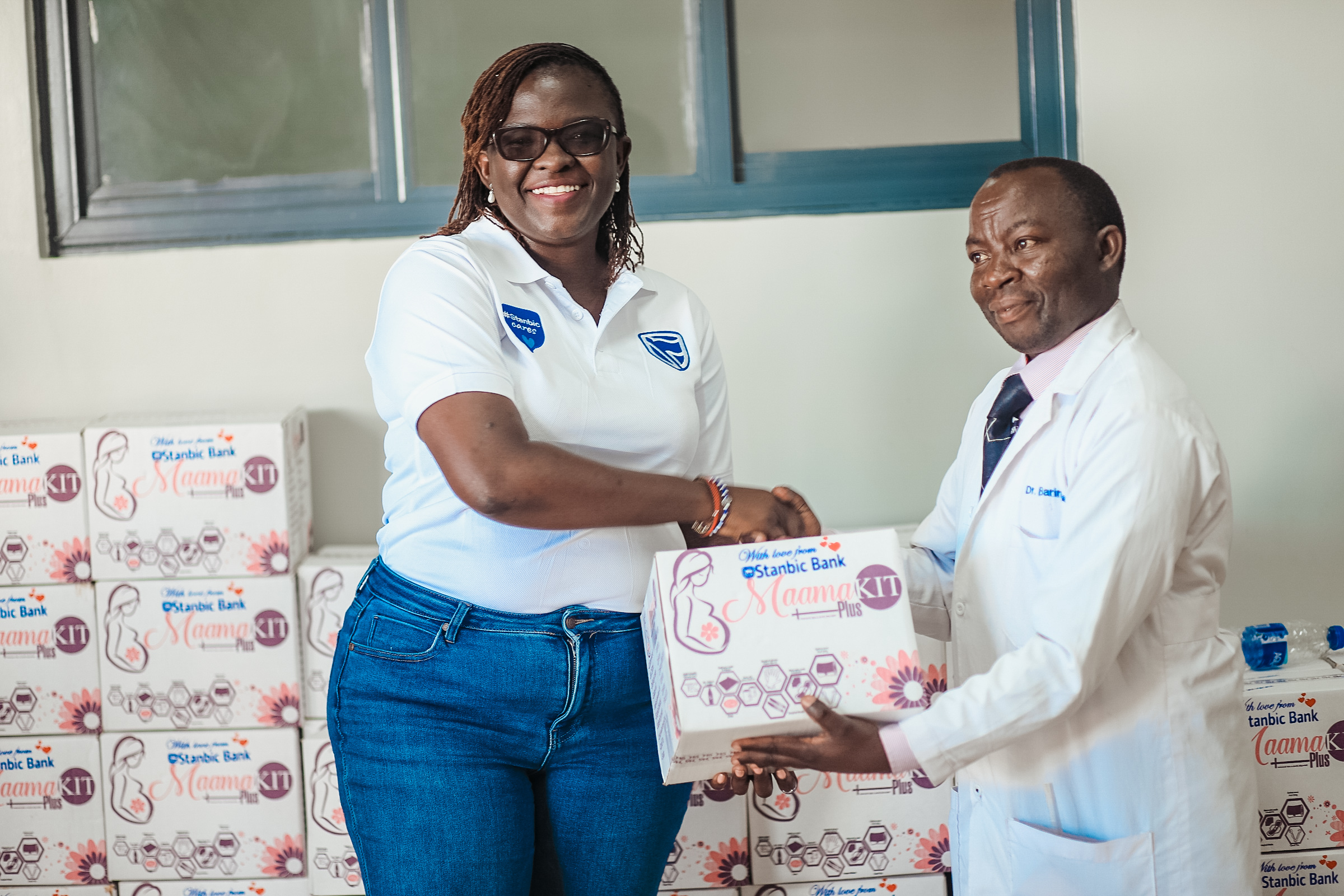 Diana Ondoga, Manager Corporate Social Investment at Stanbic Bank Uganda handing over a Mama Kit to the Rubare Health Center incharge.