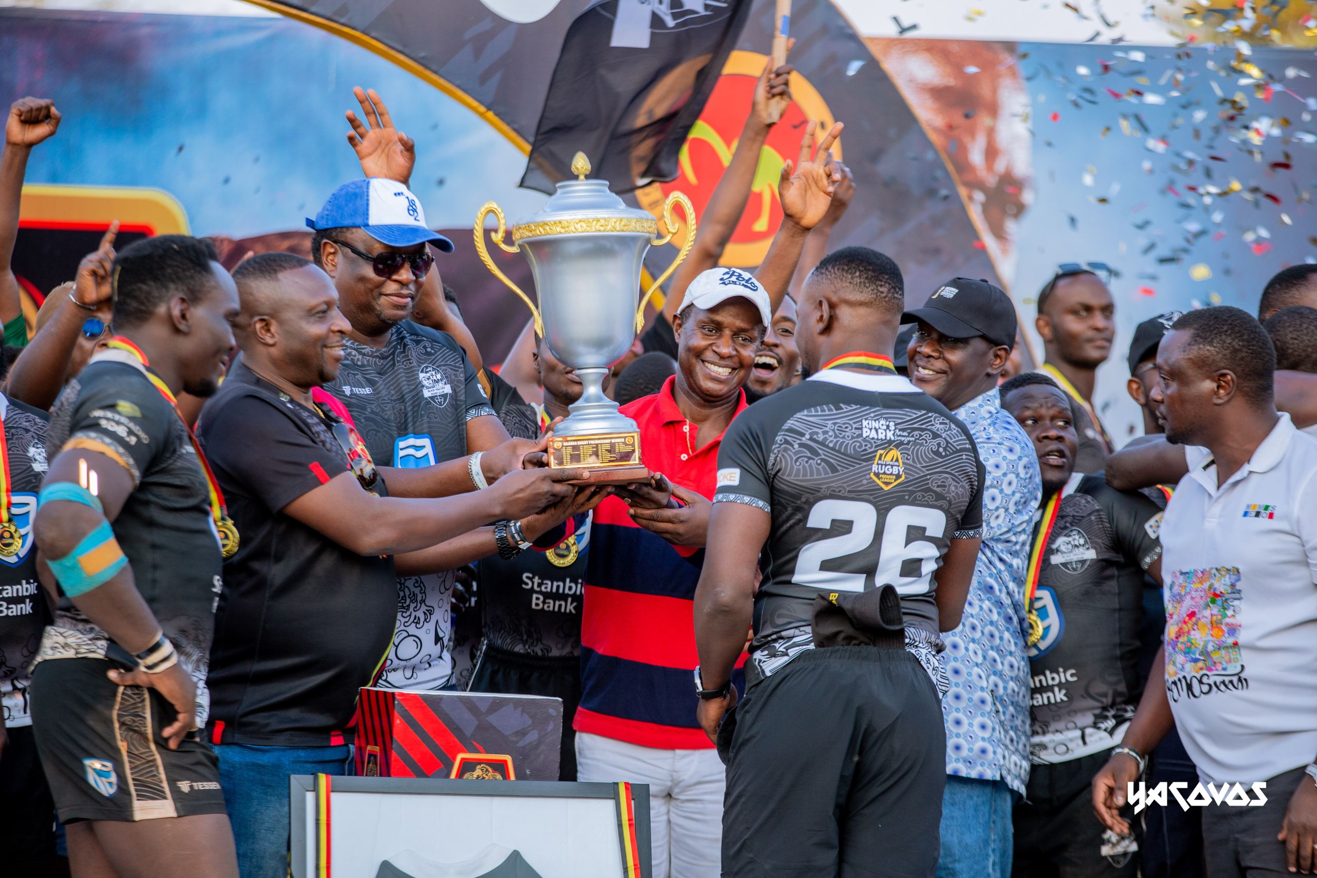 Mumba Kalifungwa, Chief Executive of Stanbic Bank, and Prince David Wasajja present the National Rugby Premiership trophy to Stanbic Black Pirates captain Isaac Massanganzira following the team's championship v