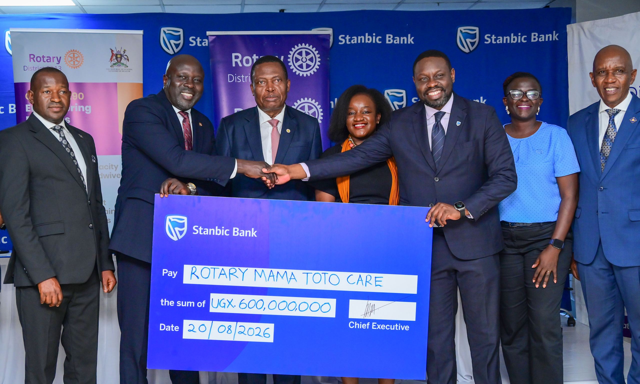 Paul Muganwa (3rd R) Stanbic Bank Uganda Executive Director handing over a partnerhip cheque to Rotary District 9213 Governor Dr Gerald Obai looking on is Dr Charle