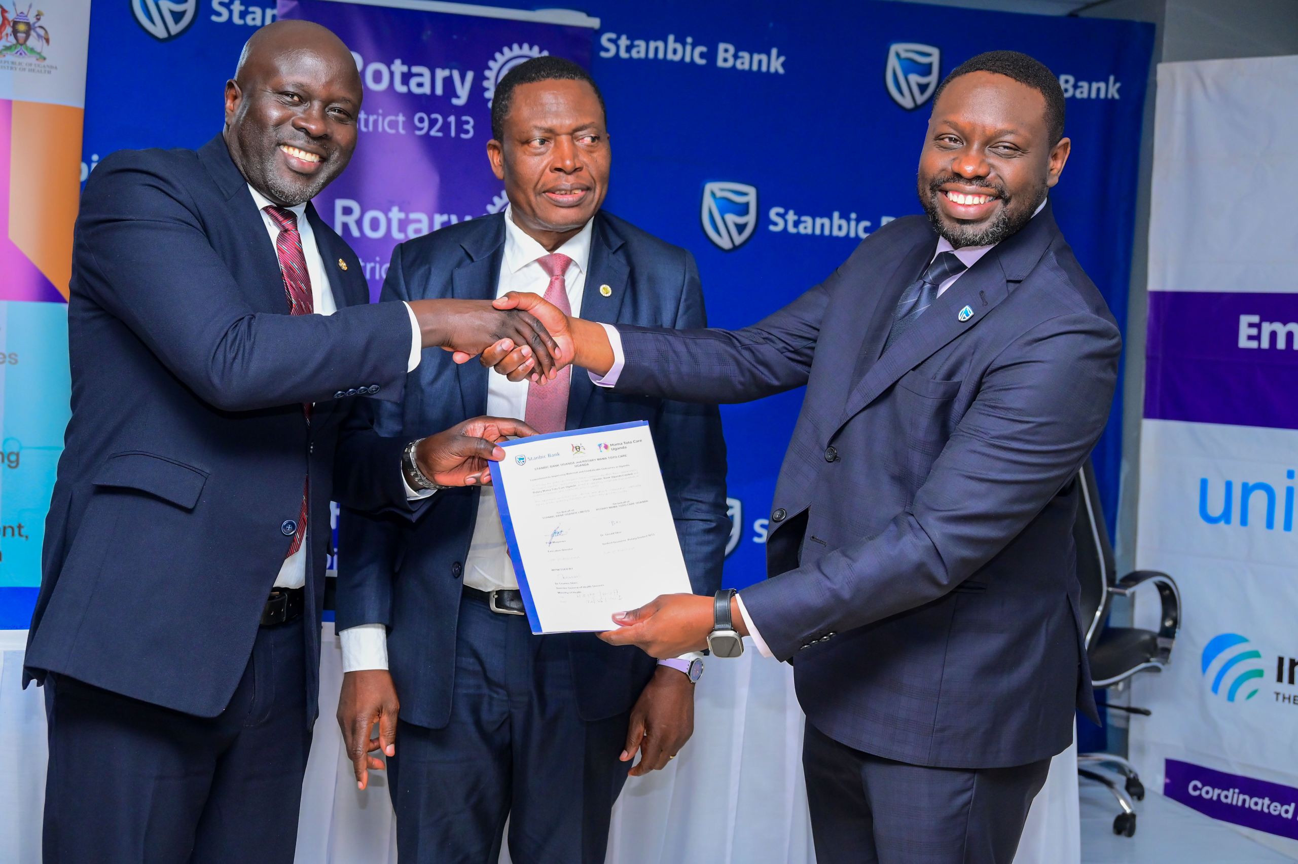 Paul Muganwa ( R), Stanbic Bank Executive Director handing shakes hands with Rotary District 9213 Governor Dr Gerald Obai, looking on is Dr Charles Olaro the Ministry of Health Director General Health Services
