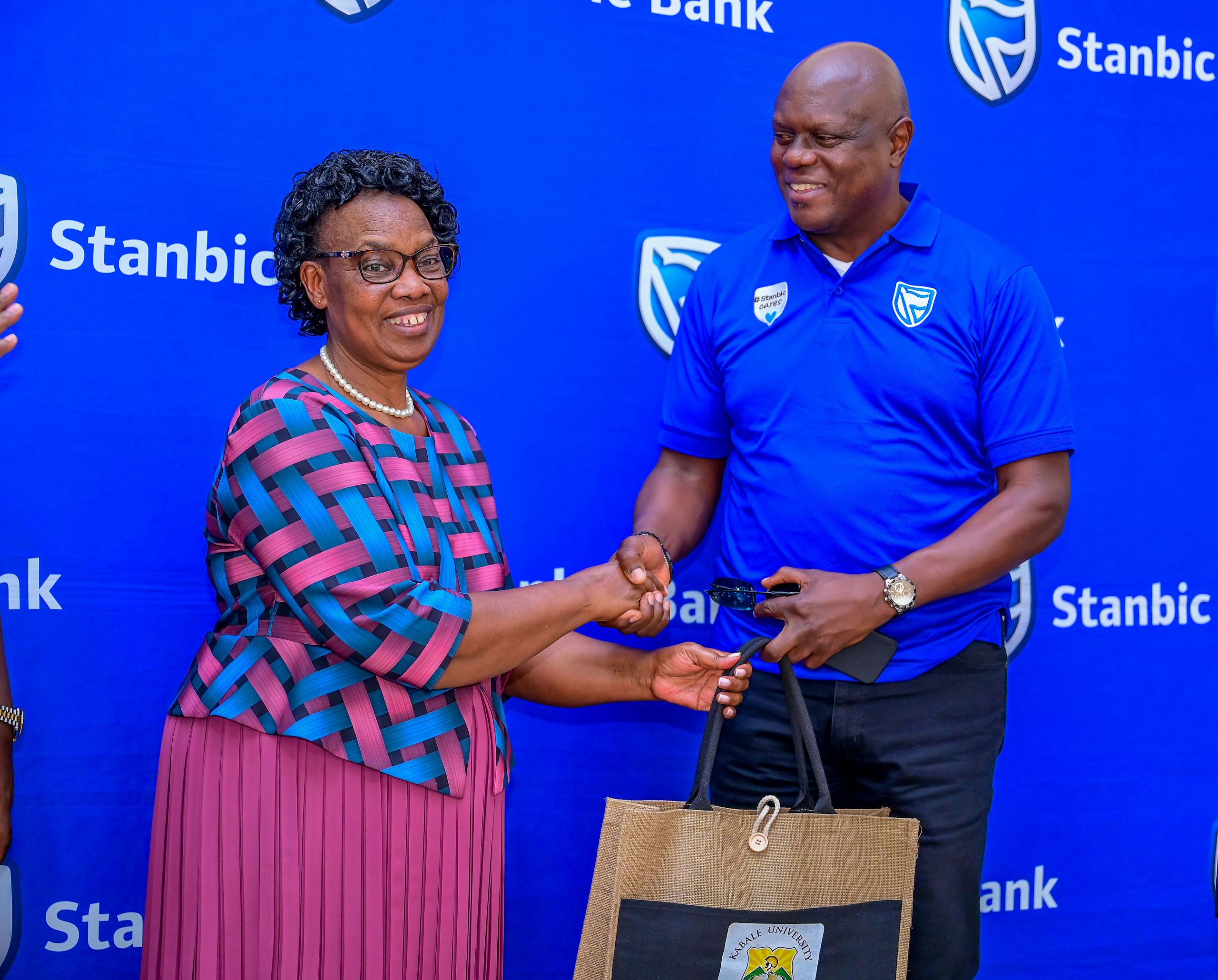 Kabale University Deputy Vice Chancellor Associate Professor Helen Musanabera Byamugisha handing over a gift to SUHL Chief Executive Mark Ocitti Ongom
