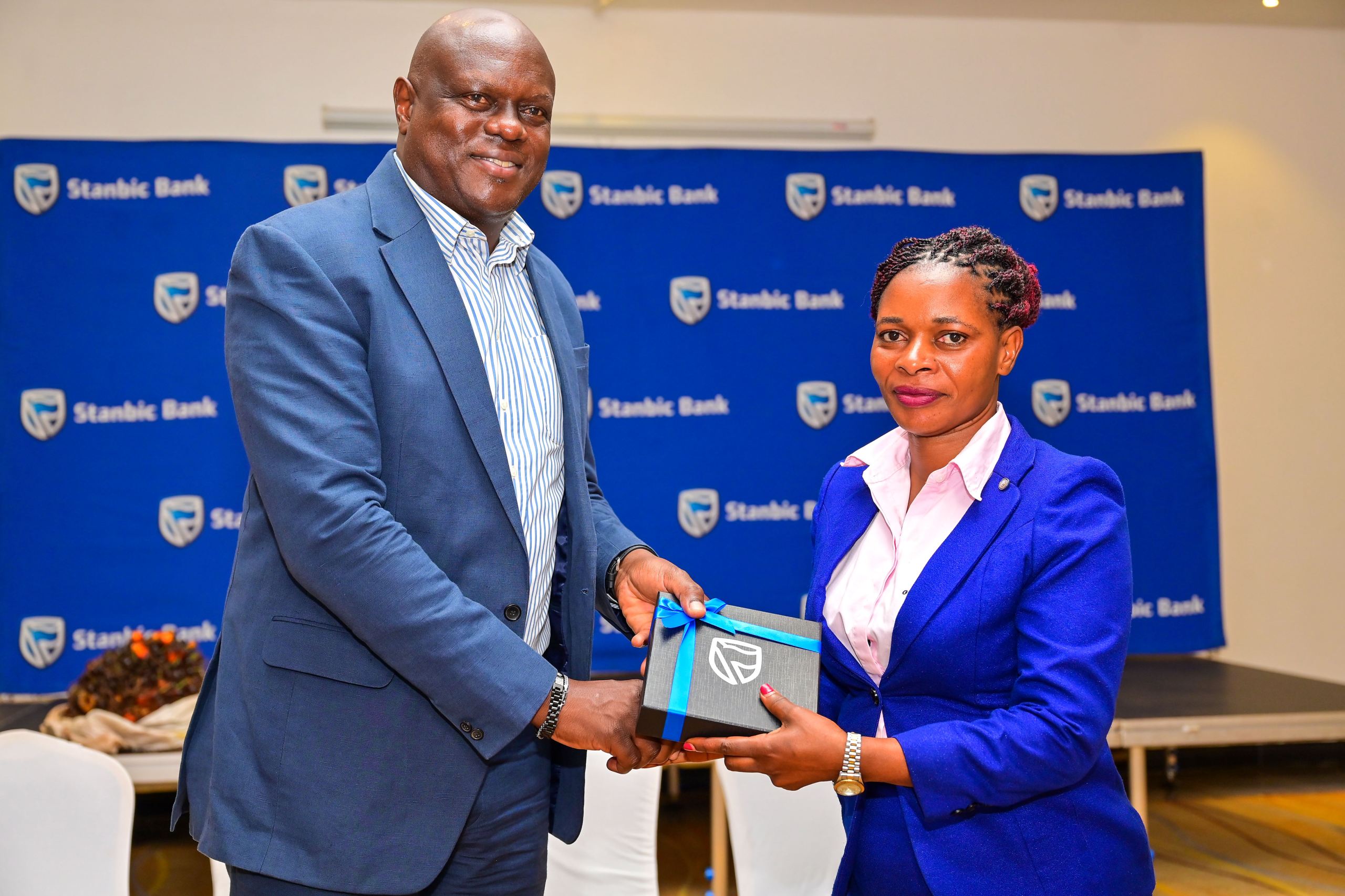 Mark Ocitti, the Stanbic Uganda Holdings Limited (SUHL) Chief Executive handing over a gift to Milly Nambatya, Manager of Sesse Oil Palm Growers SACCO during a client engagement in Kalangala Mark Ocitti, the Stanbic Uganda Holdings Limited (SUHL) Chief Executive handing over a gift to Milly Nambatya, Manager of Sesse Oil Palm Growers SACCO during a client engagement in Kalangala