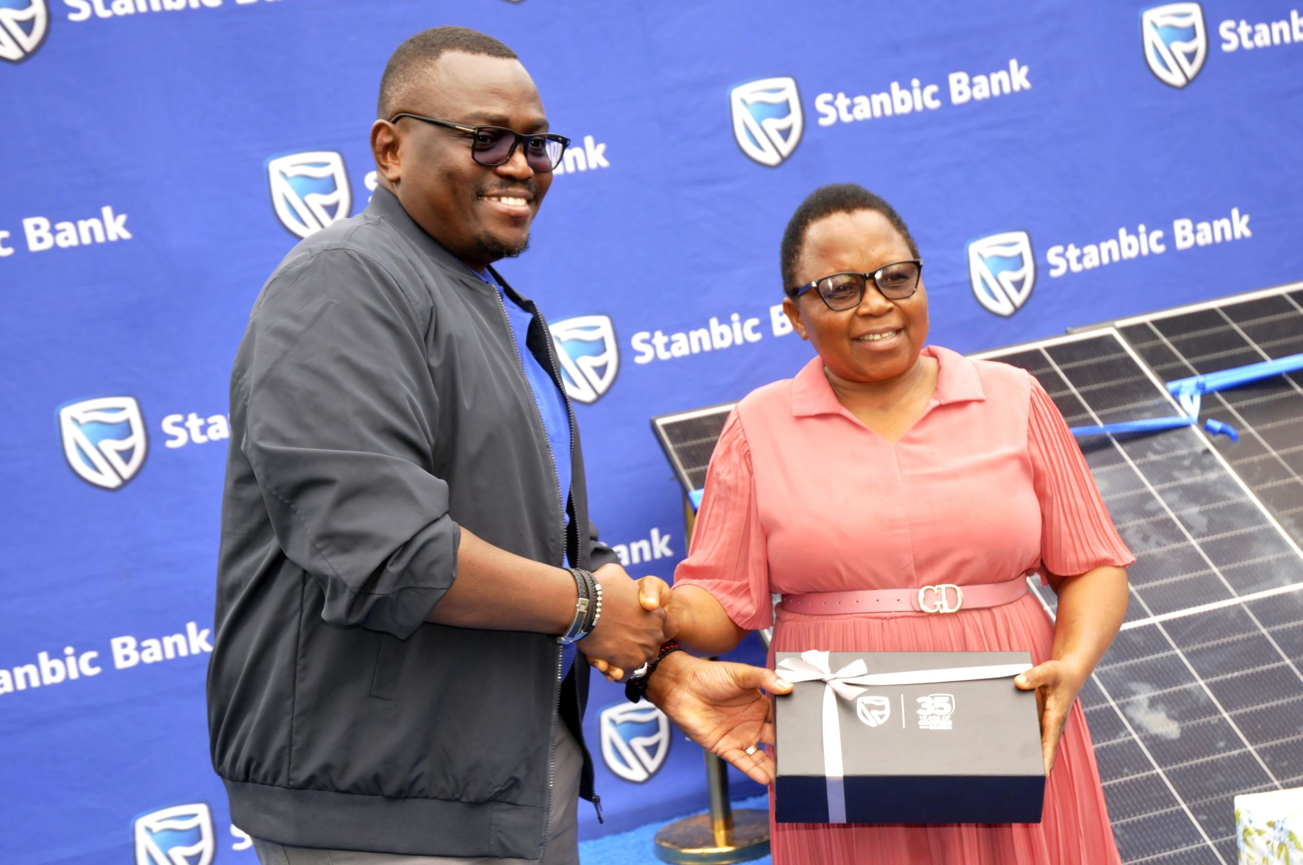 Stanbic’s Executive Head of Business and Commercial Banking, Tunde Thorpe, handing over a gift to the acting District Education Officer, Joy Wamalugu Stanbic's Executive Head of Business and Commercial Banking, Tunde Thorpe, handing over a gift to the acting District Education Officer, Joy Wamalugu